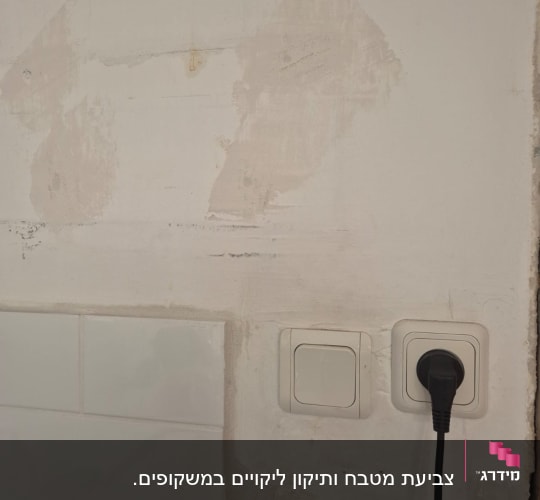 קיר עם תיקוני צבע ושקע חשמל
